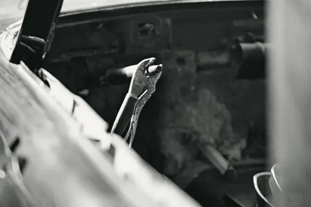 Locking pliers clamped onto a part inside a car's engine bay