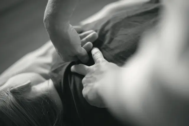 A physio's hands working on a patient's back